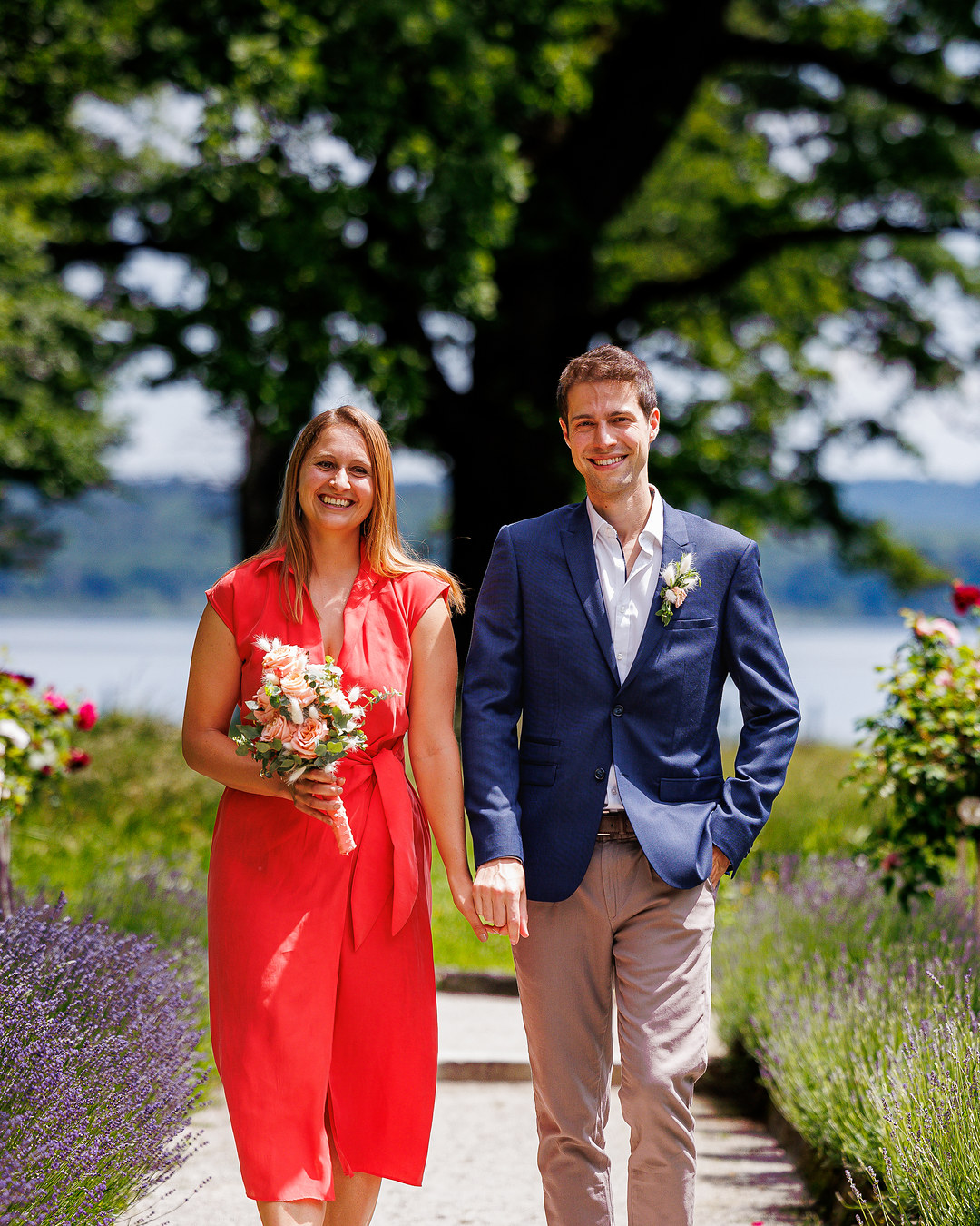 Brautpaar geht Hand in Hand durch einen Rosengarten mit Lavendel